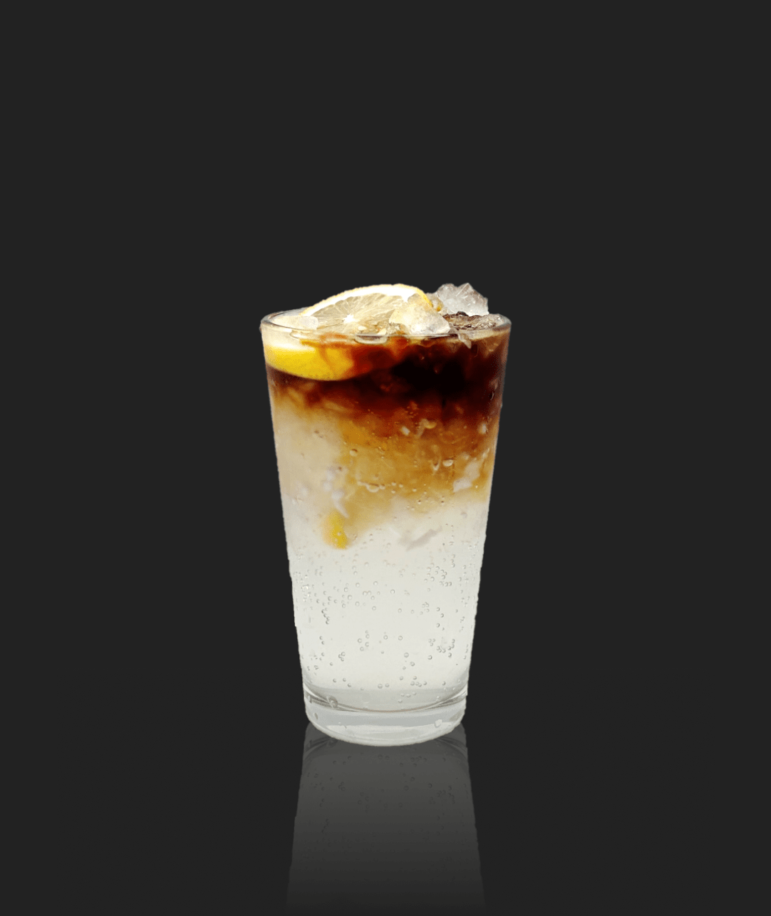 Tall glass of layered soda with a lemon slice and ice, set against a dark background.