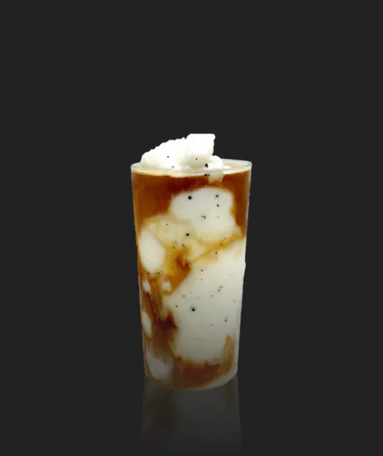 Tall glass of iced coffee with cream swirls and whipped cream on top against a dark background.