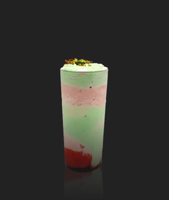 Layered pastel smoothie in a tall glass with whipped cream and toppings, against a dark background, shown from the side.