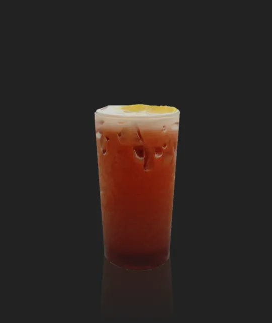 Tall glass of iced tea with a lemon wedge on top and ice cubes against a dark background.