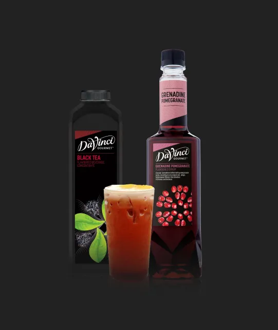 Two DaVinci Gourmet syrup bottles (Black Tea and Grenadine Pomegranate) with a glass of iced tea on a dark background.