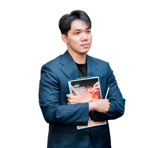 Man in a blue suit stands with arms crossed, holding a magazine against his chest.
