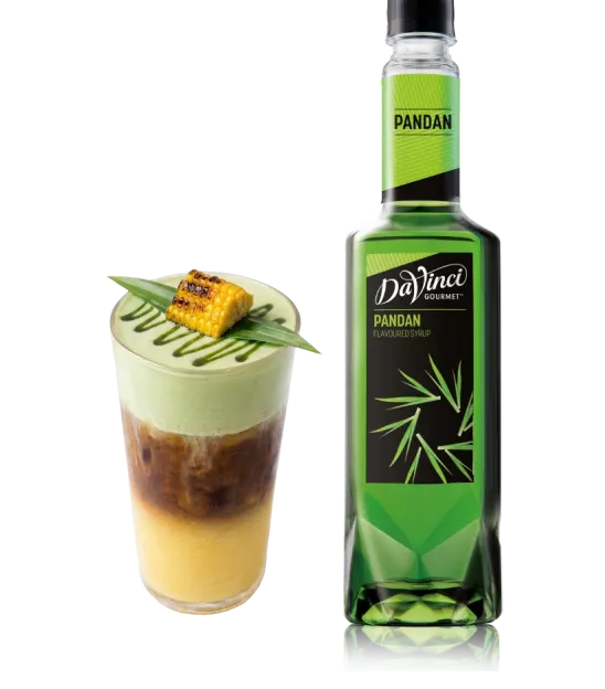 Layered dessert beverage with green pandan cream, corn garnish on a skewer, beside a bottle of DaVinci Pandan syrup.