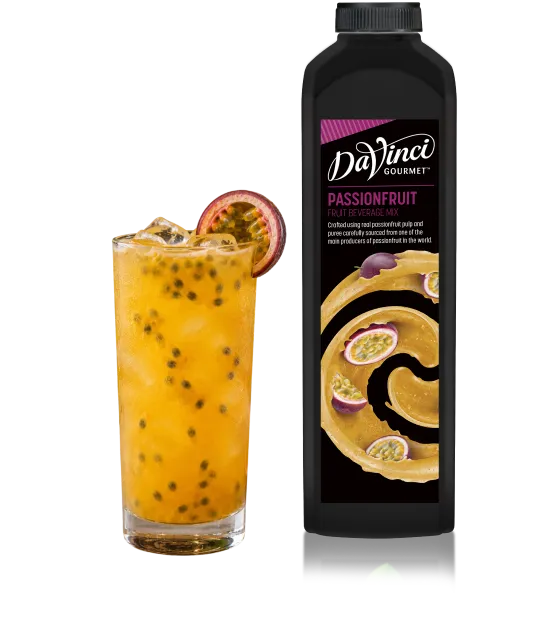 Glass of ice-filled passionfruit drink with a slice of fruit, next to a DaVinci Gourmet Passionfruit beverage mix bottle.